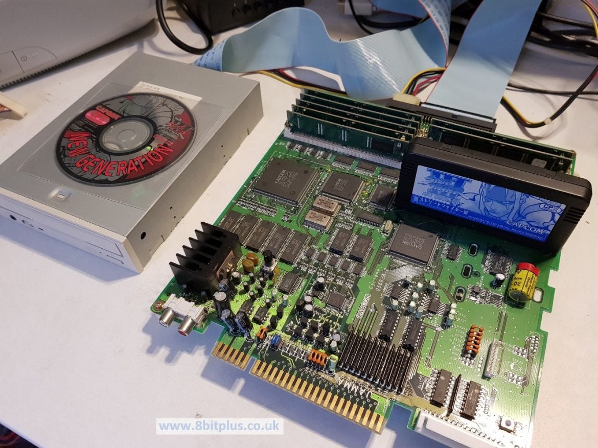 CPS3 com leitor de CD, cartucho azul e módulos de memória